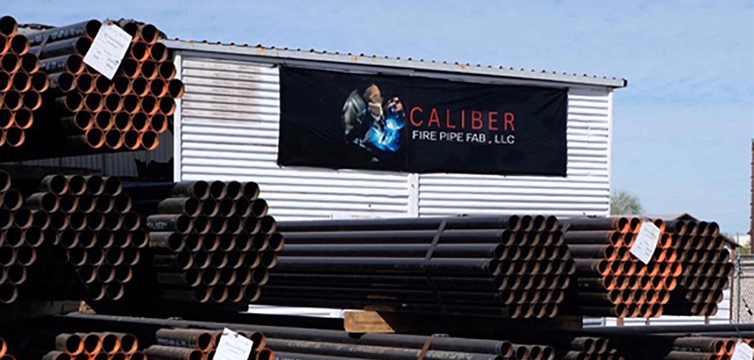 who-are-we-caliber Steel pipe outside of warehouse with Caliber sign on it